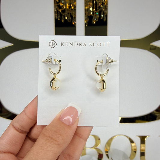Kendra Scott earrings on a card held by a hand with a decorative background