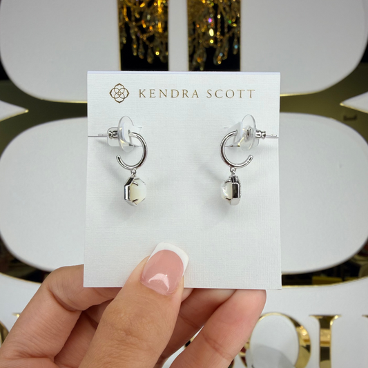 Kendra Scott earrings held on a branded card with a decorative background