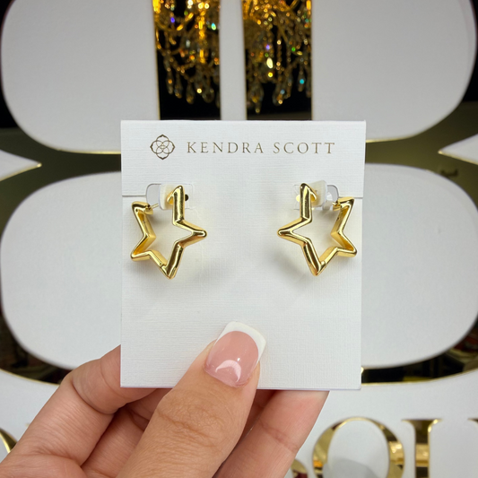 Gold star earrings on a Kendra Scott card held by a hand with a blurred background