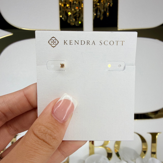 Kendra Scott earring card held by a hand with a decorative background
