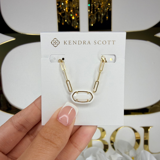 Kendra Scott earring on a card held by a hand with a decorative background
