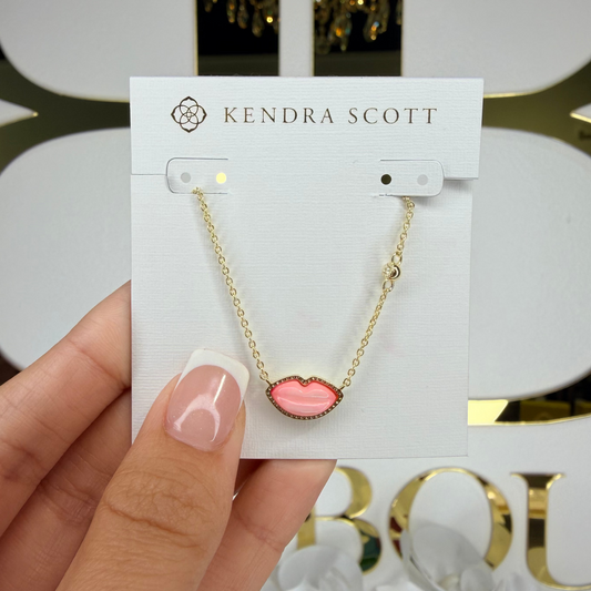 Kendra Scott necklace on a card held by a hand with a decorative background