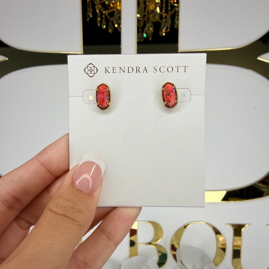 Kendra Scott earrings on a card held by a hand with a blurred background