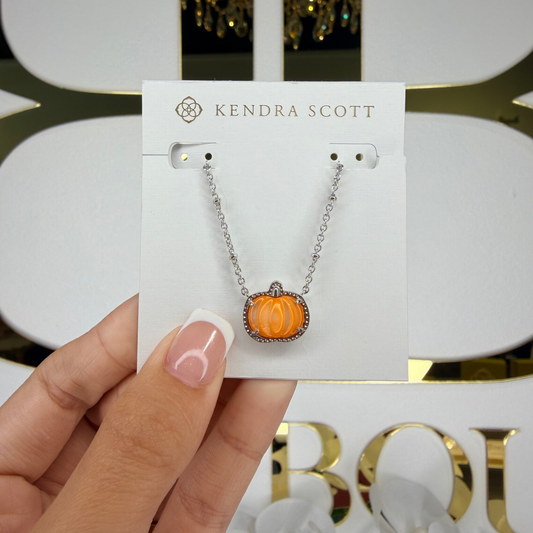Kendra Scott necklace with pumpkin charm held on a branded card.