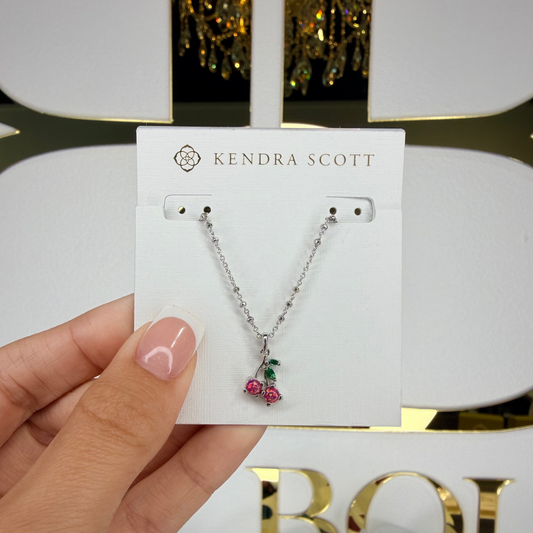 Kendra Scott necklace on a card held by a hand with a blurred background
