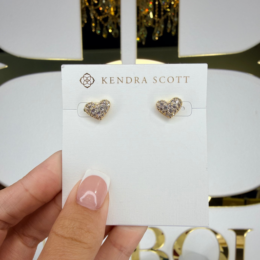 Heart-shaped earrings on a Kendra Scott card held by a hand with a blurred background