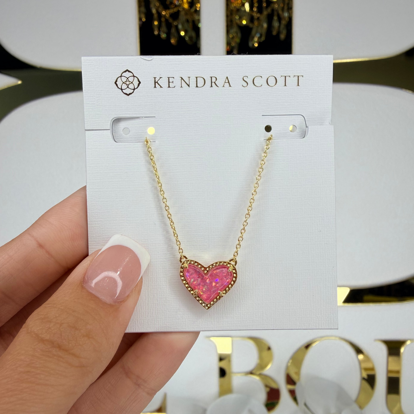Kendra Scott necklace with a pink heart pendant held on a branded card.