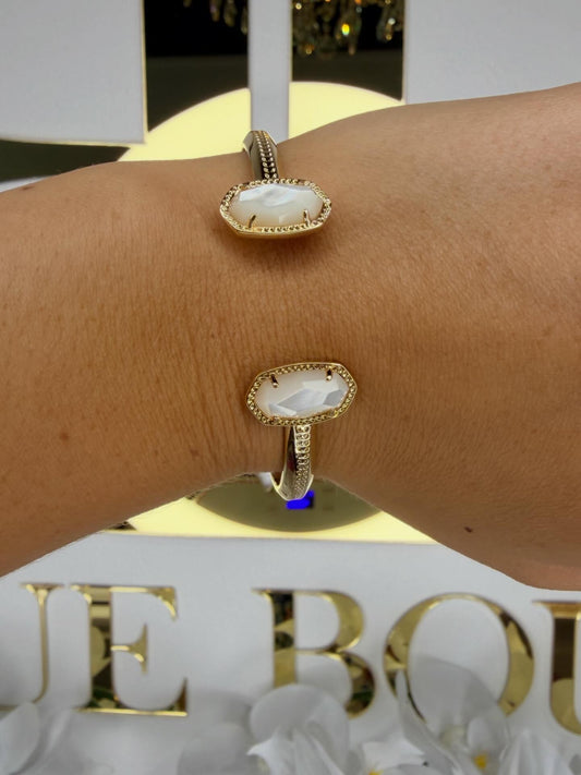 Gold bracelet with a central stone on a wrist, with 'Blue Box' branding in the background.