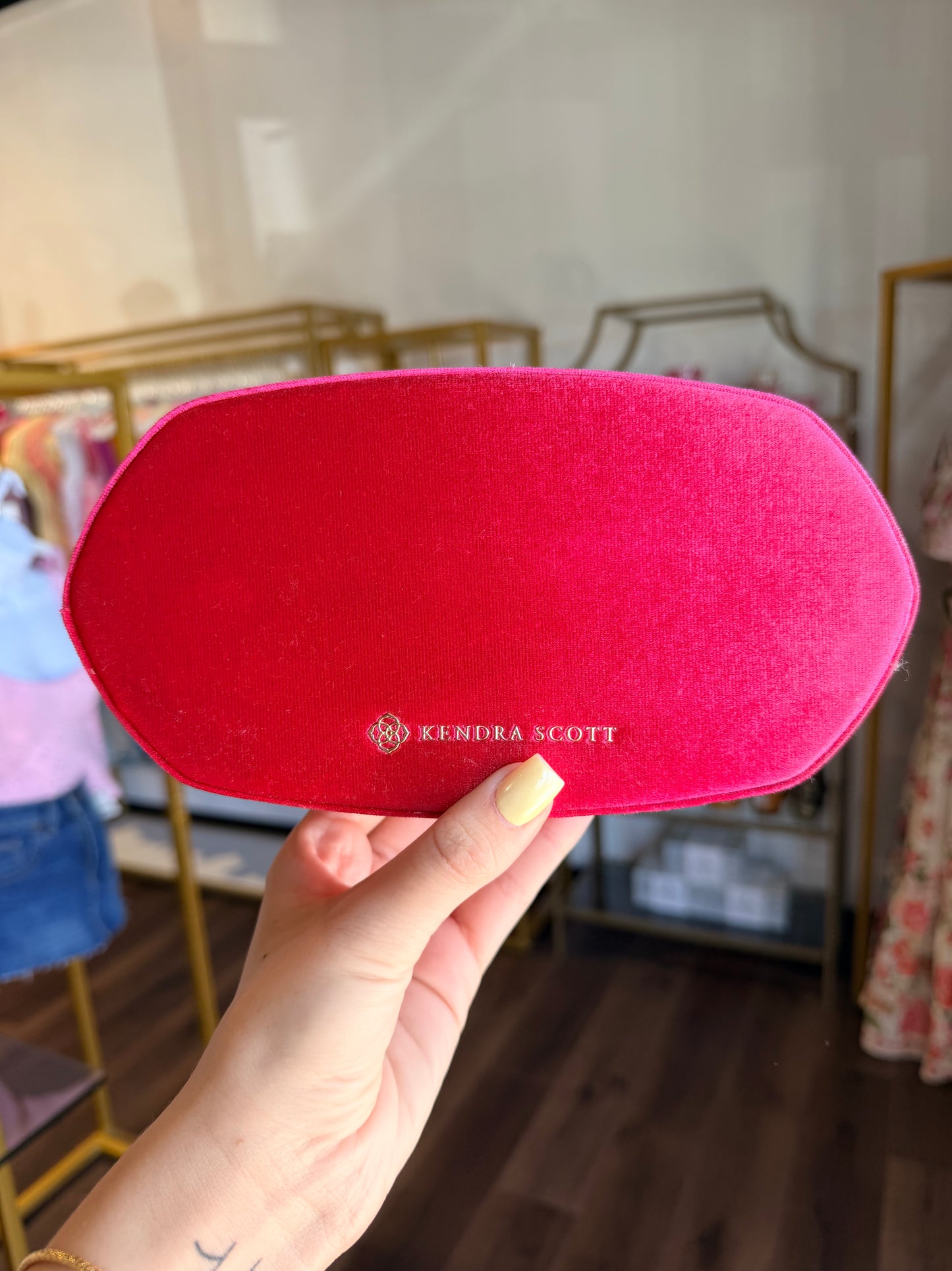 Kendra Scott jewelry box in hot pink in front of store 