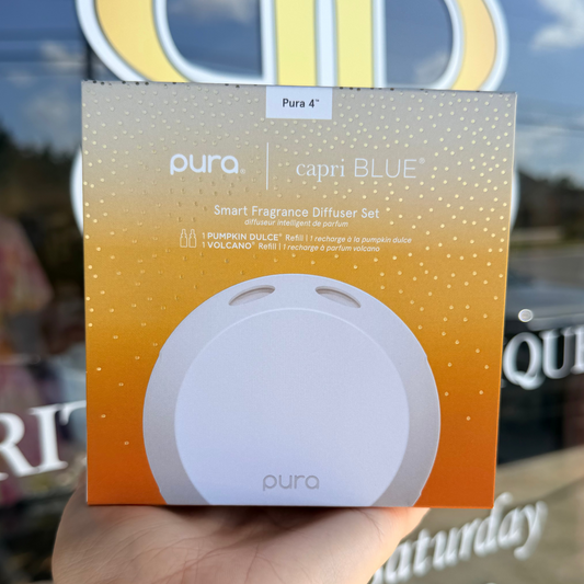 Pura capri BLUE smart fragrance diffuser set packaging held in front of a store window.
