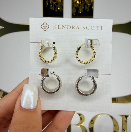 Kendra Scott earrings on a display card held by a hand with white nail polish.
