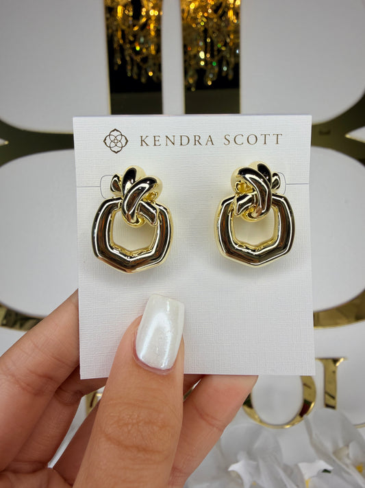 Gold and black earrings on a Kendra Scott card held by a hand with white nail polish.