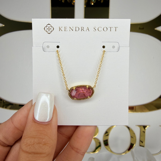 Kendra Scott necklace on a card held by a hand with a decorative background