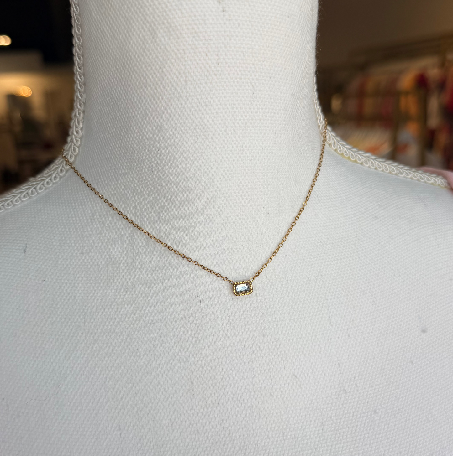 Gold necklace with a small pendant on a mannequin bust