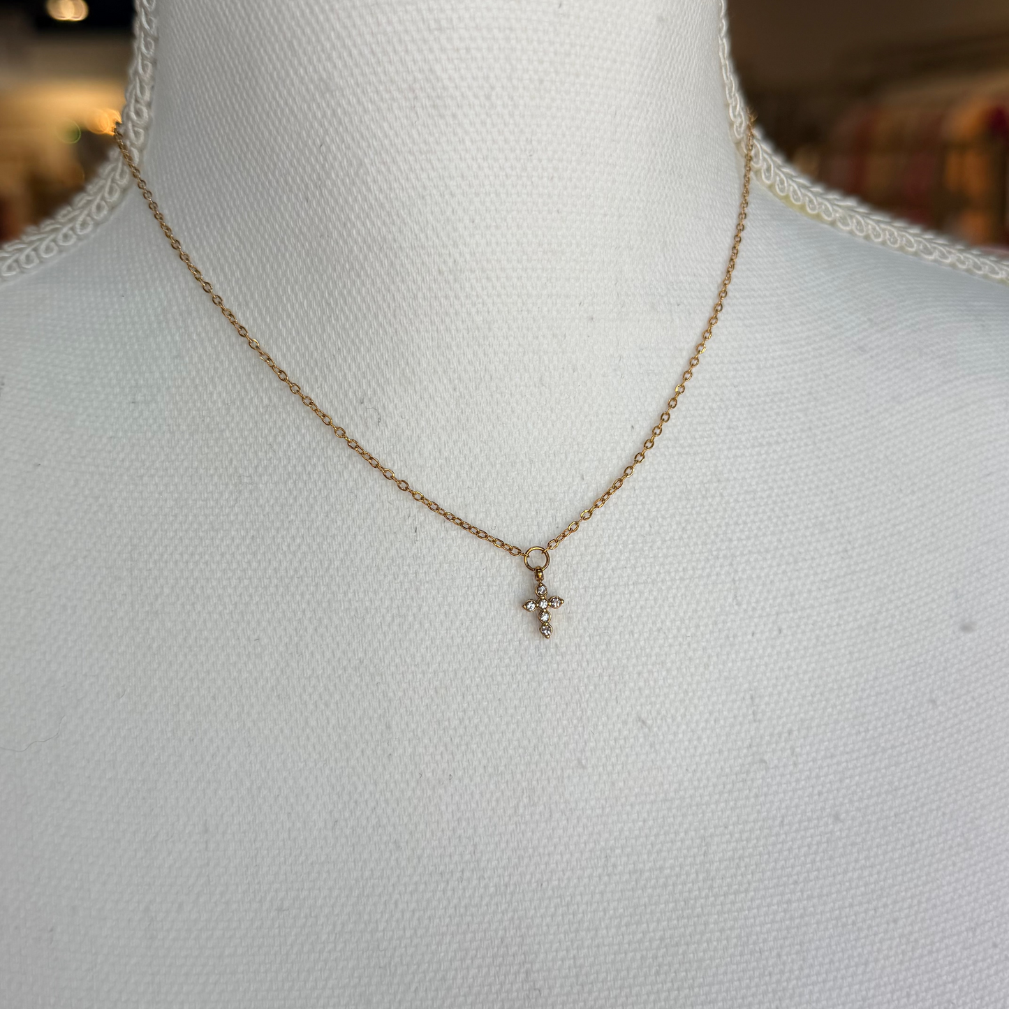 Gold necklace with a small pendant on a mannequin bust