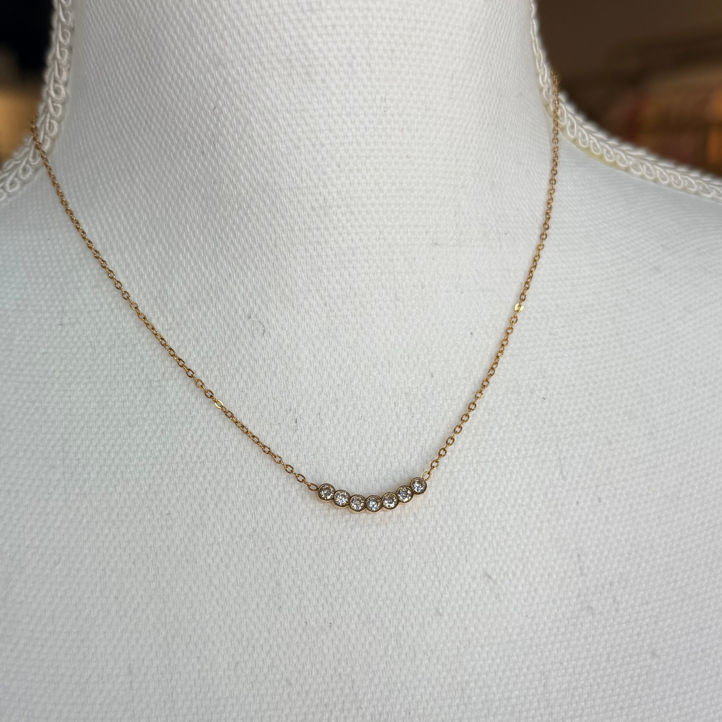 Gold necklace on a mannequin with a blurred background.