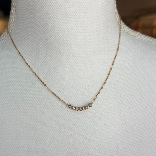 Gold necklace on a mannequin with a blurred background.