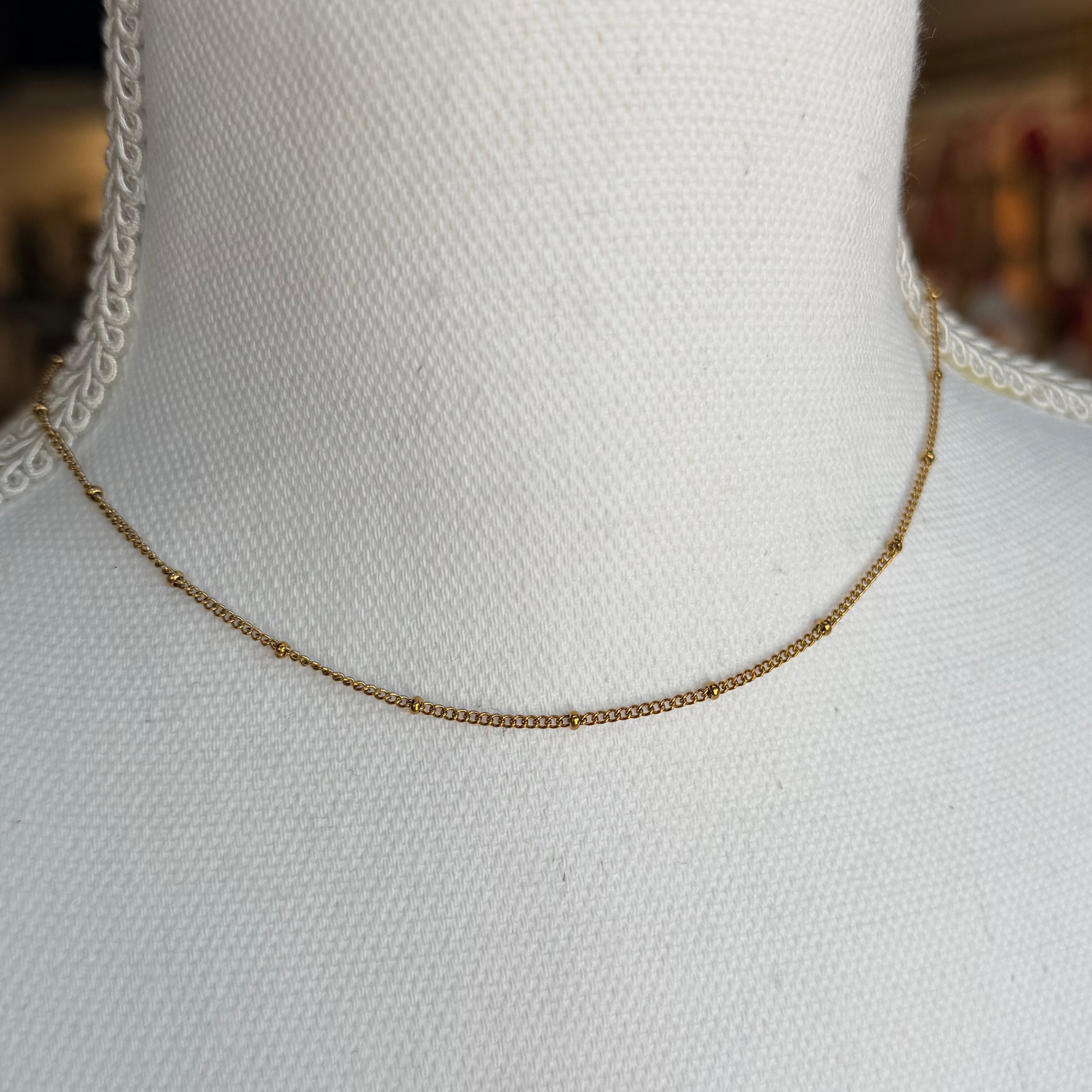 Gold necklace on a mannequin with a blurred background