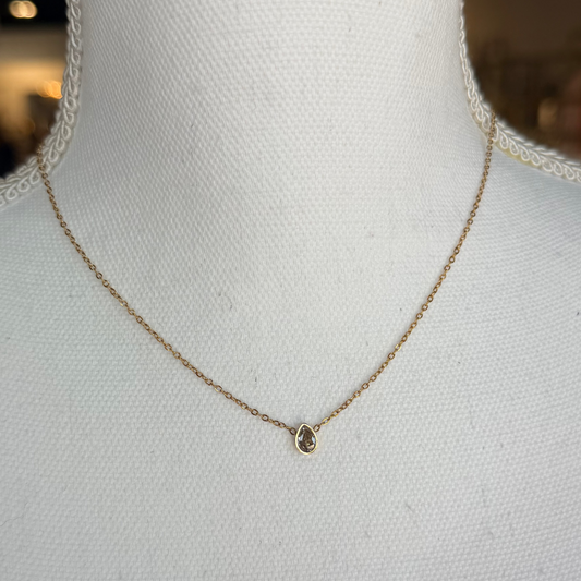 Gold necklace on a mannequin bust with a blurred background.