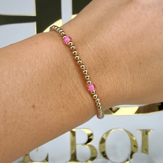 Bracelet with pink beads on a wrist against a decorative background