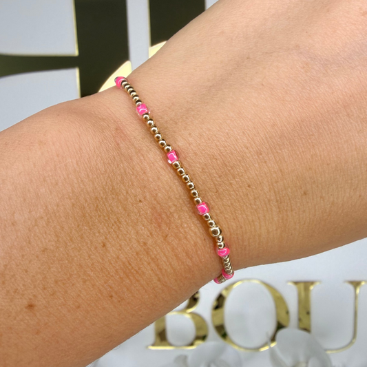 Bracelet with pink beads on a wrist, blurred background with 'Boutique' text