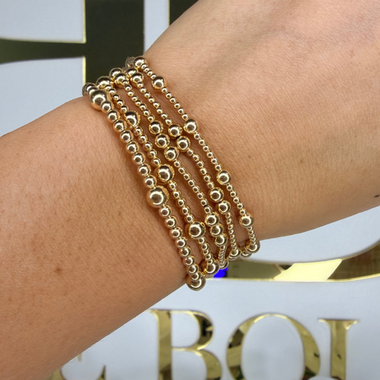 Gold bracelets on a wrist with a blurred background