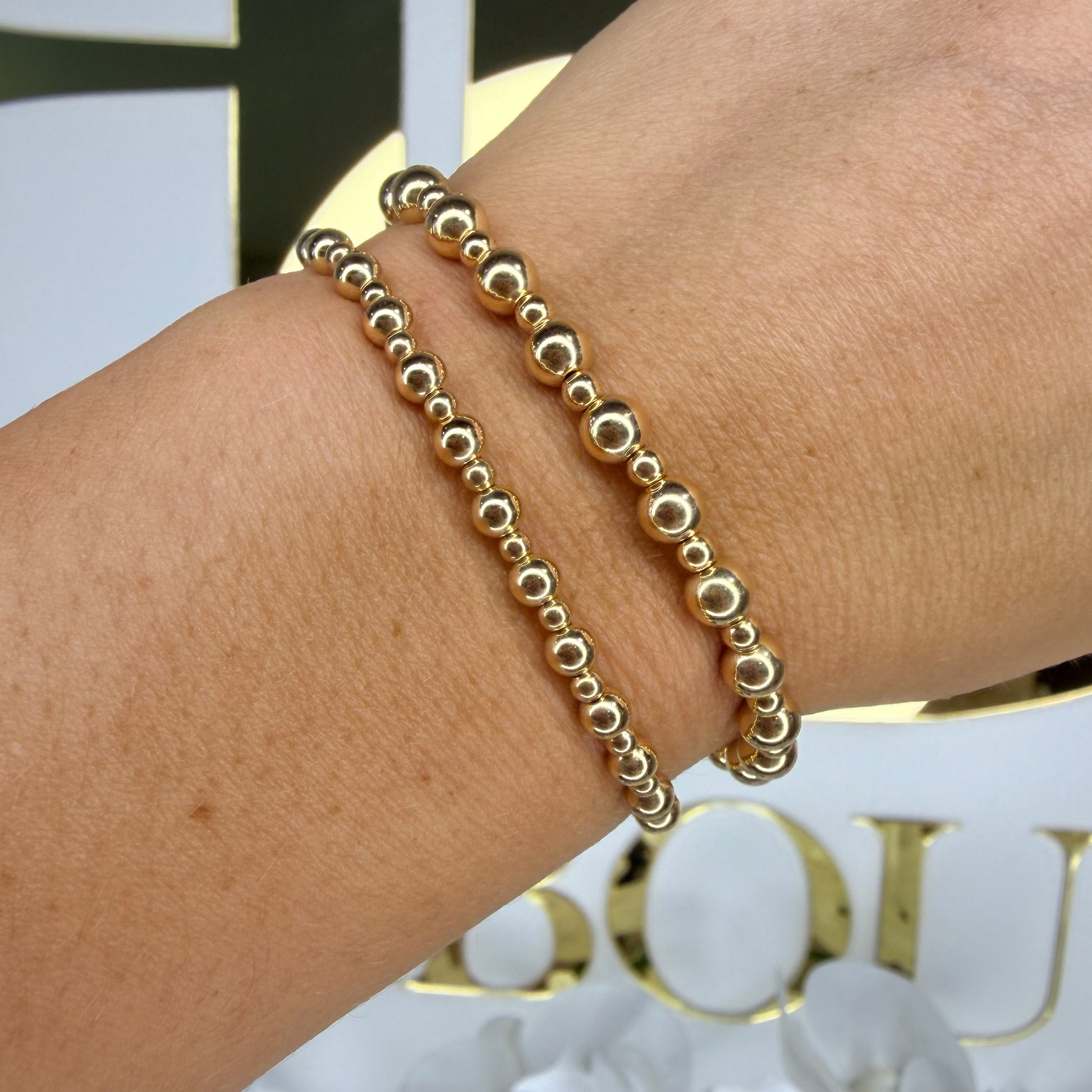Gold beaded bracelet on a wrist with a blurred background