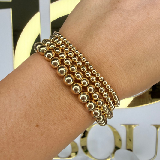 Gold beaded bracelet on a wrist with a blurred background