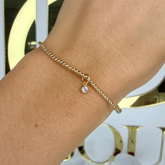 Gold bracelet on a wrist with a blurred background