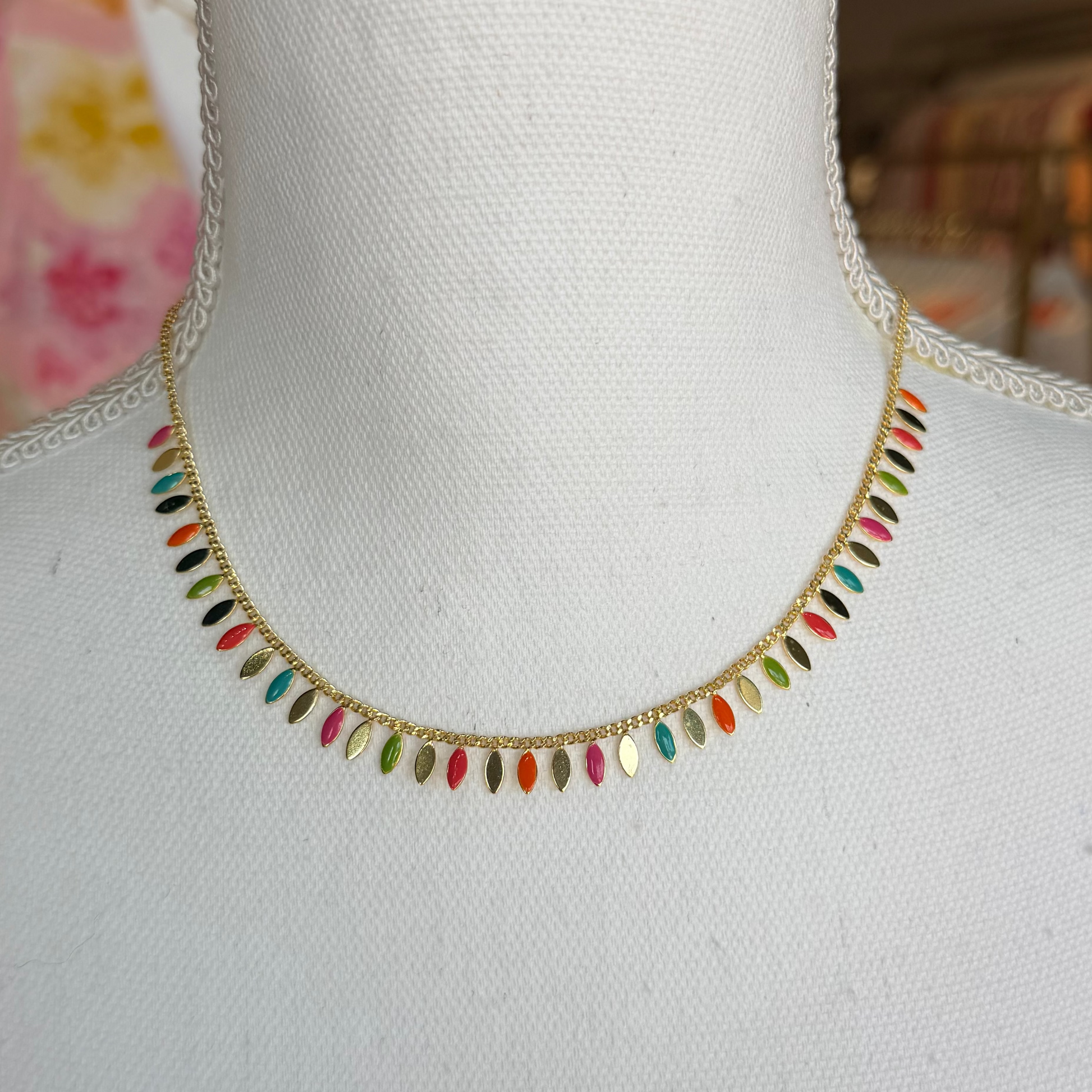 Colorful beaded necklace on a mannequin with a blurred background.
