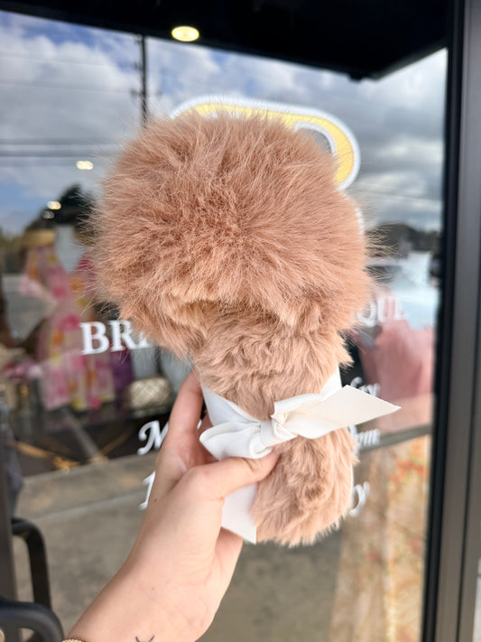 Fluffy pink slippers held in front of a store window with 'Bri' visible.