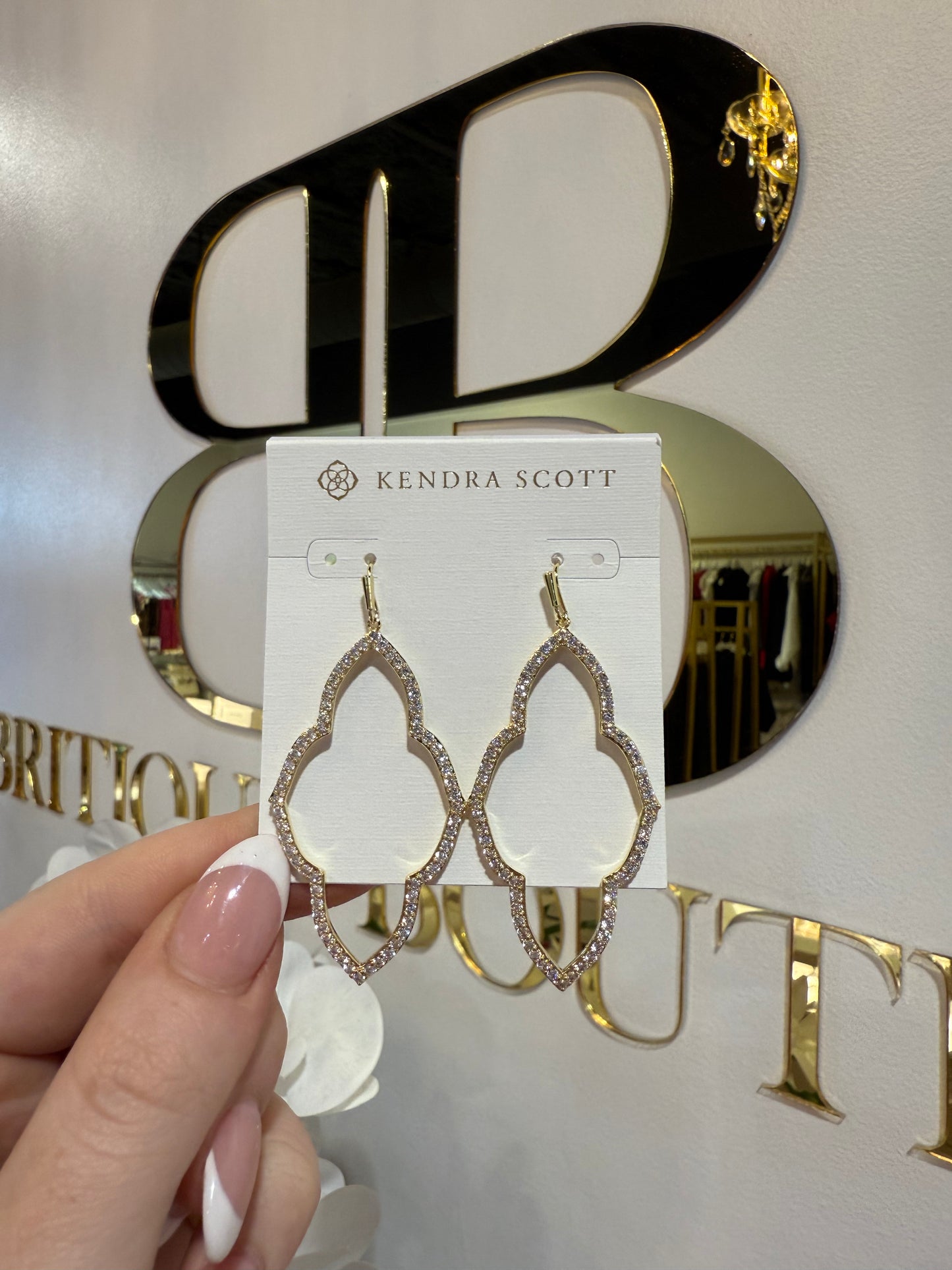BOUTIQUE KENDRA SCOTT ABBIE GOLD OPEN FRAME EARRINGS IN WHITE CRYSTAL IN HAND