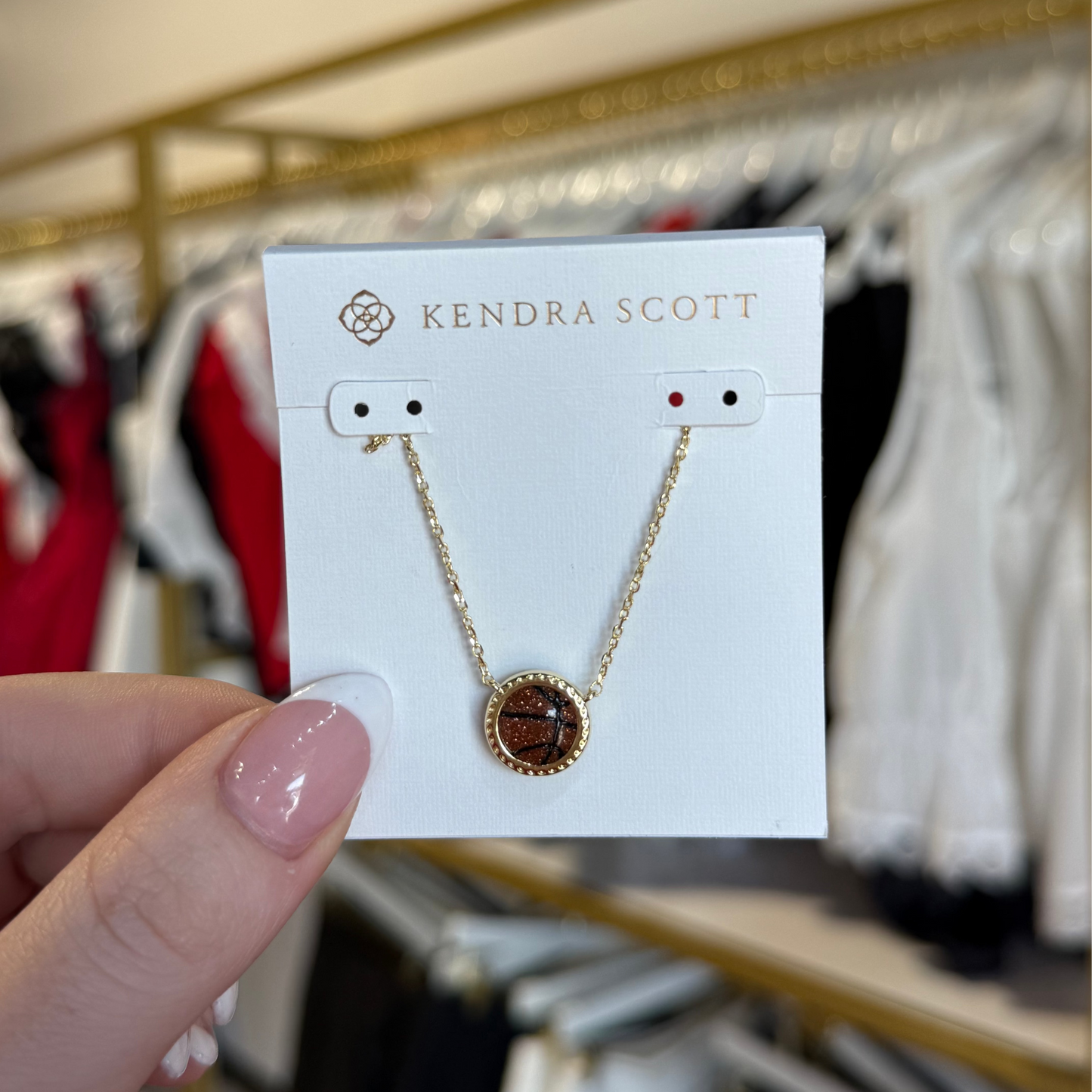 BOUTIQUE KENDRA SCOTT BASKETBALL GOLD SHORT PENDANT NECKLACE IN ORANGE GOLDSTONE IN HAND