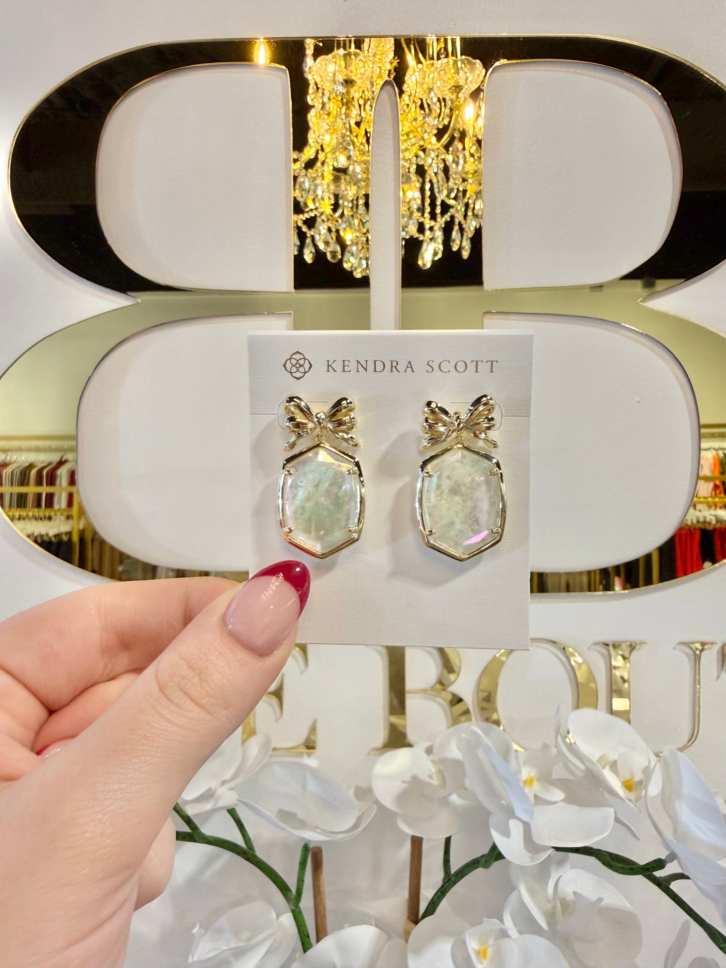 BOUTIQUE KENDRA SCOTT DAPHNE GOLD BOW DROP EARRINGS IN IVORY ILLUSION IN HAND
