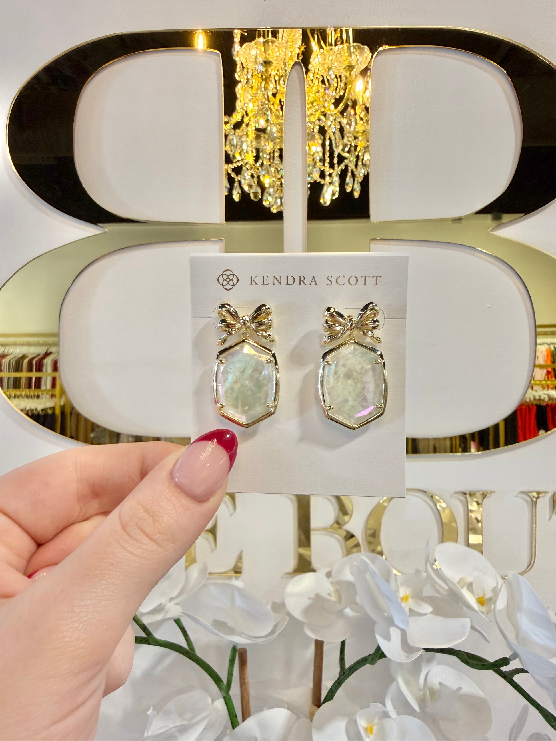 BOUTIQUE KENDRA SCOTT DAPHNE GOLD BOW DROP EARRINGS IN IVORY ILLUSION IN HAND