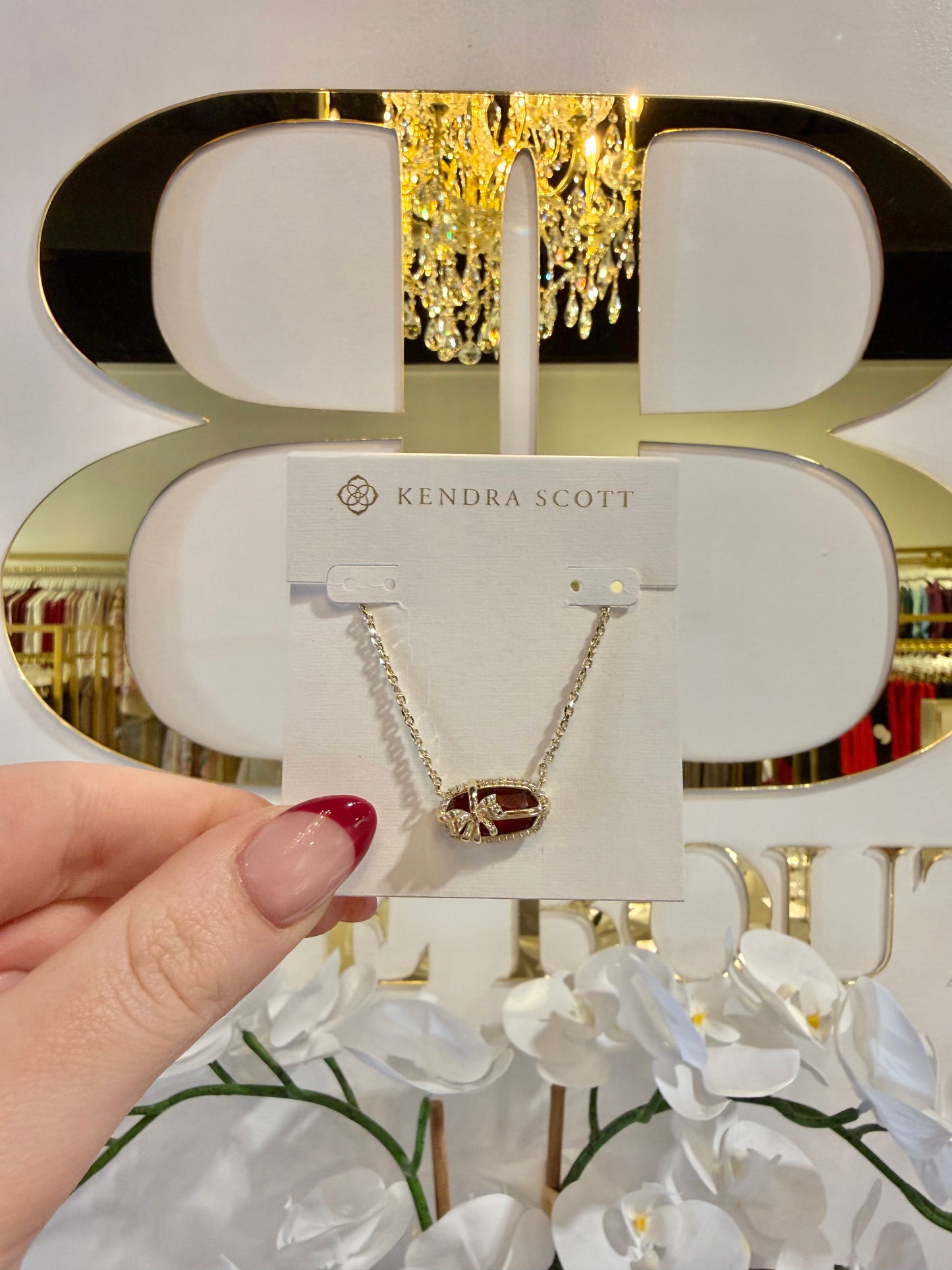 BOUTIQUE KENDRA SCOTT ELISA BOW GOLD SHORT PENDANT NECKLACE IN DARK BURGUNDY ILLUSION IN HAND