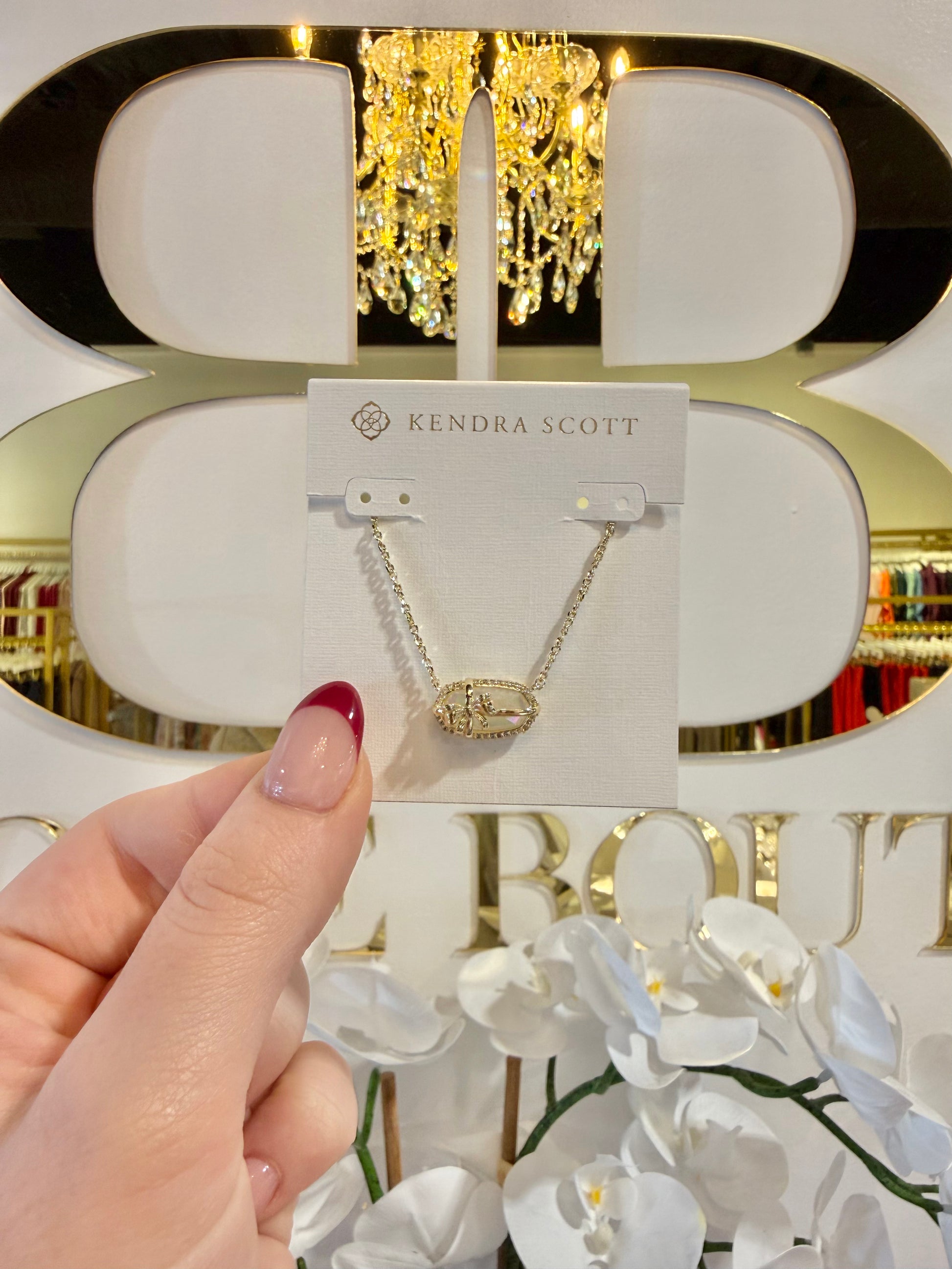 BOUTIQUE KENDRA SCOTT ELISA BOW GOLD SHORT PENDANT NECKLACE IN IVORY ILLUSION IN HAND