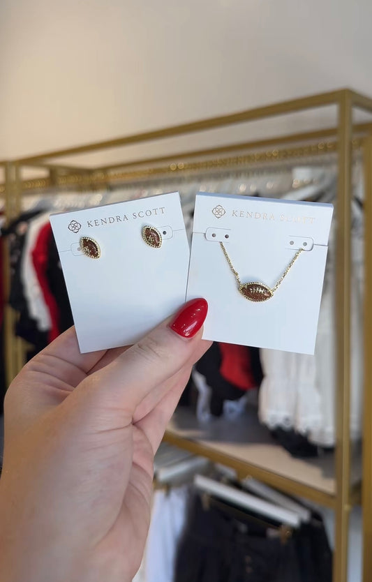 BOUTIQUE KENDRA SCOTT FOOTBALL GOLD STUD EARRINGS IN ORANGE GOLSTONE IN HAND