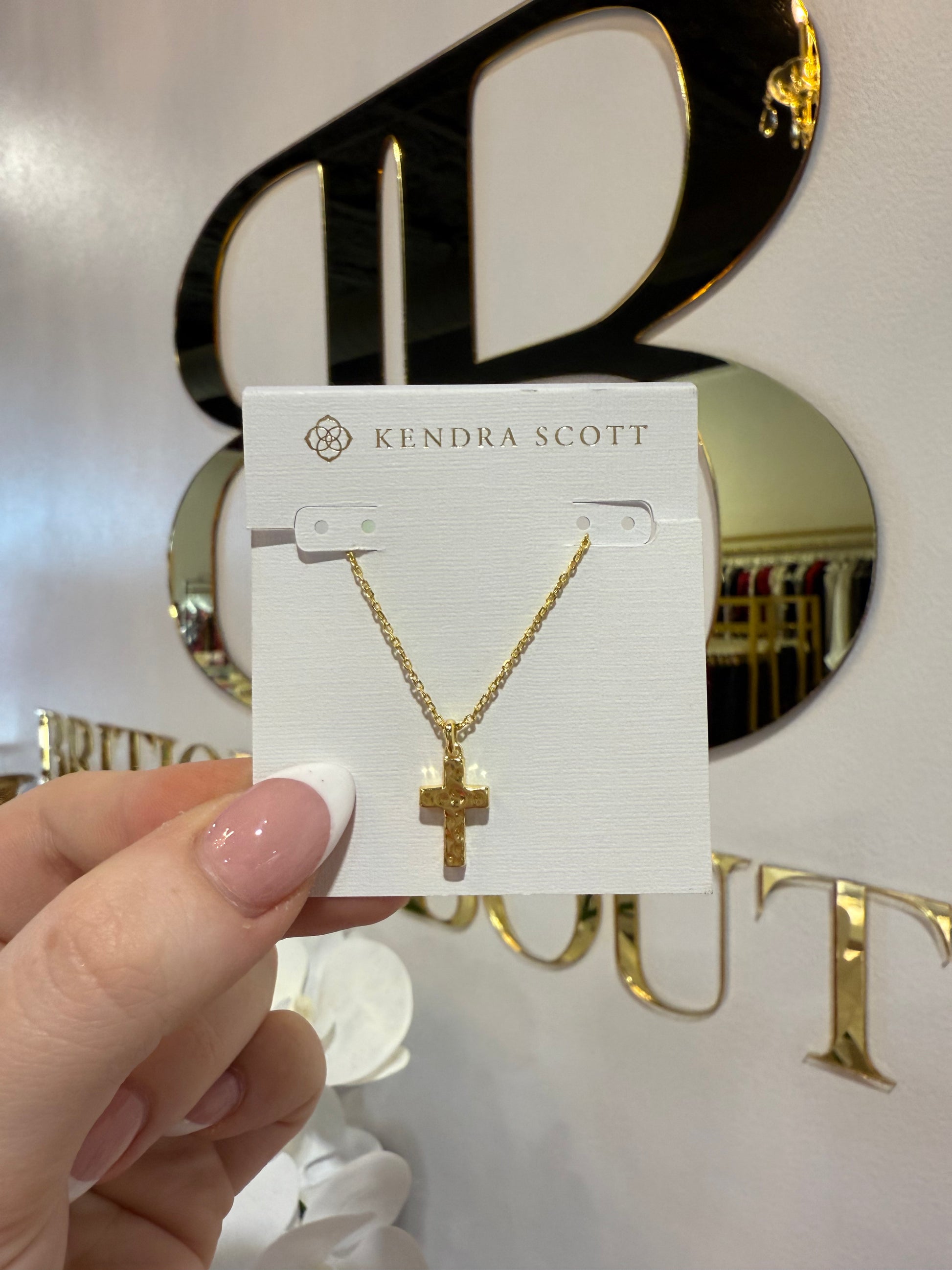 BOUTIQUE KENDRA SCOTT GOLD CROSS PENDANT NECKLACE IN HAND