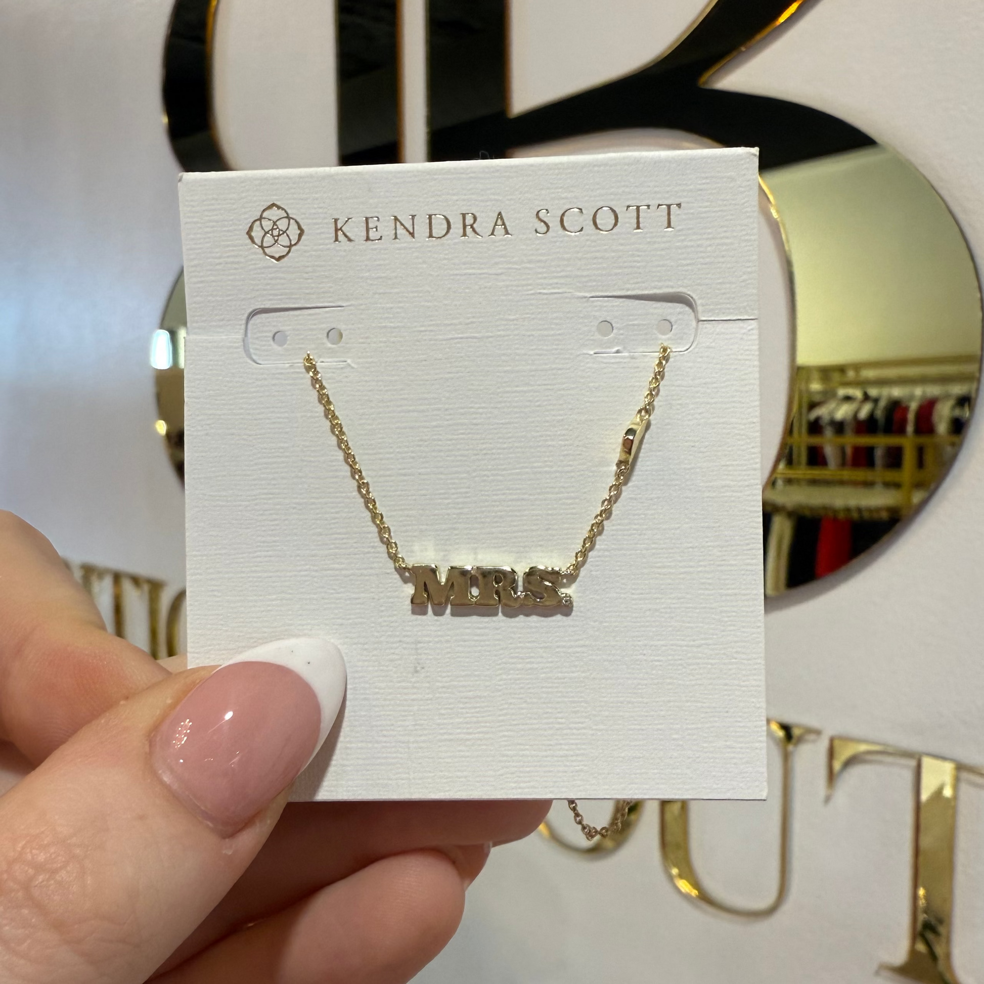BOUTIQUE KENDRA SCOTT GOLD MRS PENDANT NECKLACE IN HAND