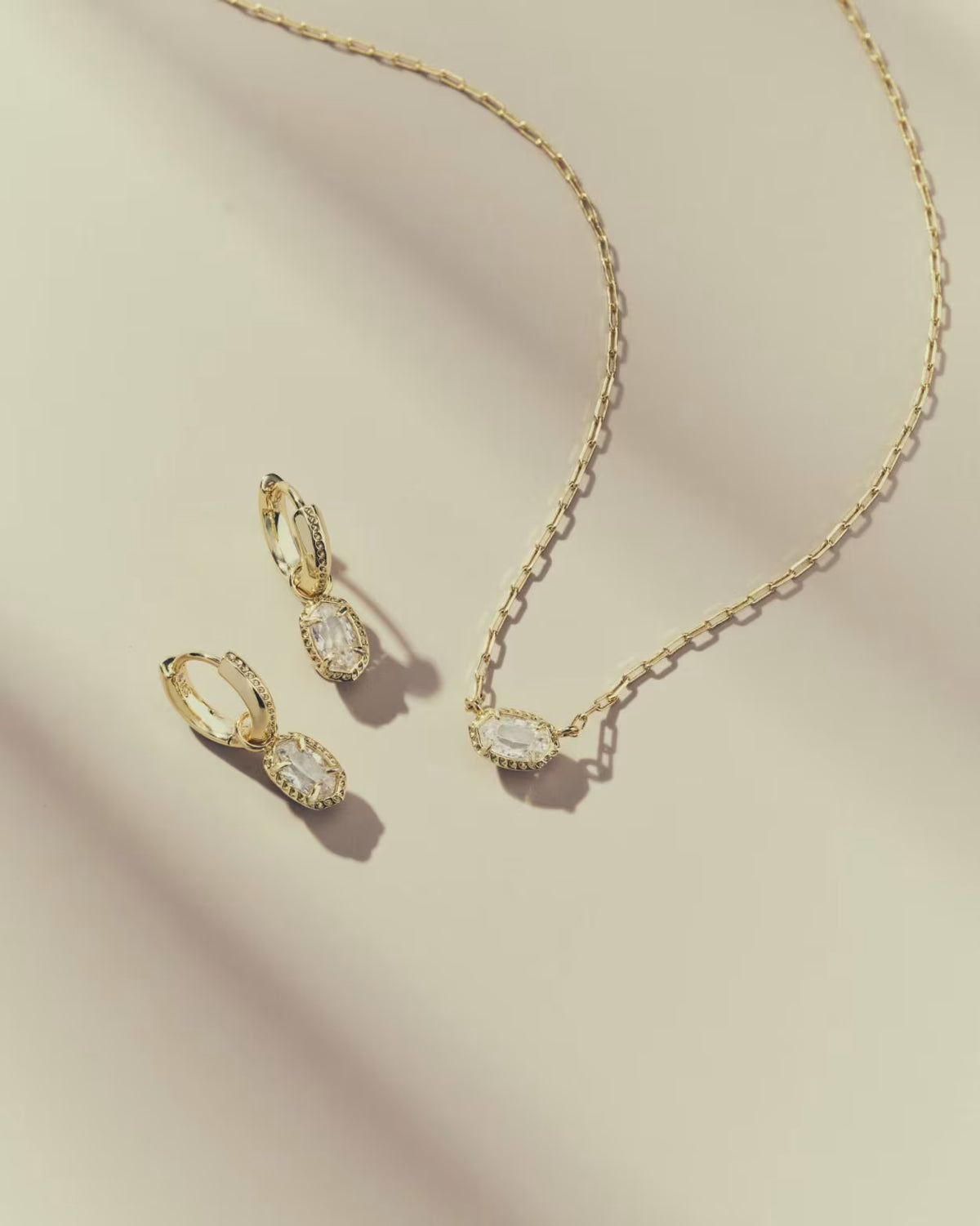 Kendra Scott Mini Ellie Luxe Huggie Earrings and Necklace set on cream background
