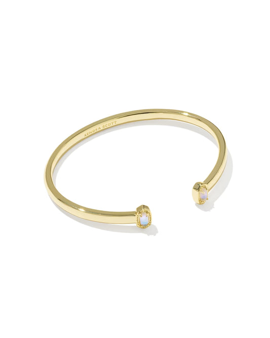 A gold-tone open cuff bangle bracelet with two small oval bezel-set light blue stones, shown on a clean white background.