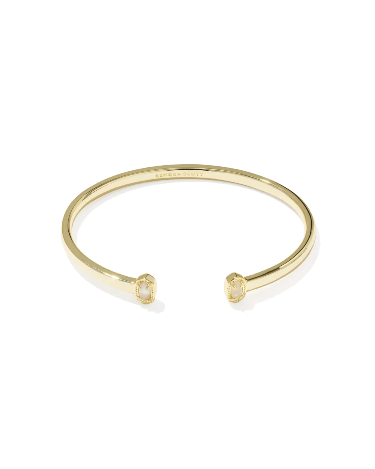 A gold open cuff bangle bracelet with small rectangular clear gemstones set in each end, shown on a clean white background. The brand name 'CHANEL' is faintly engraved inside the band.
