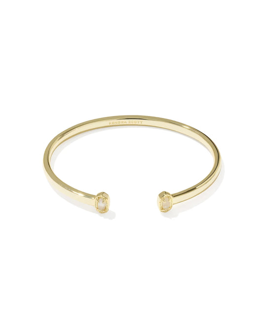 A gold open cuff bangle bracelet with small rectangular clear gemstones set in each end, shown on a clean white background. The brand name 'CHANEL' is faintly engraved inside the band.