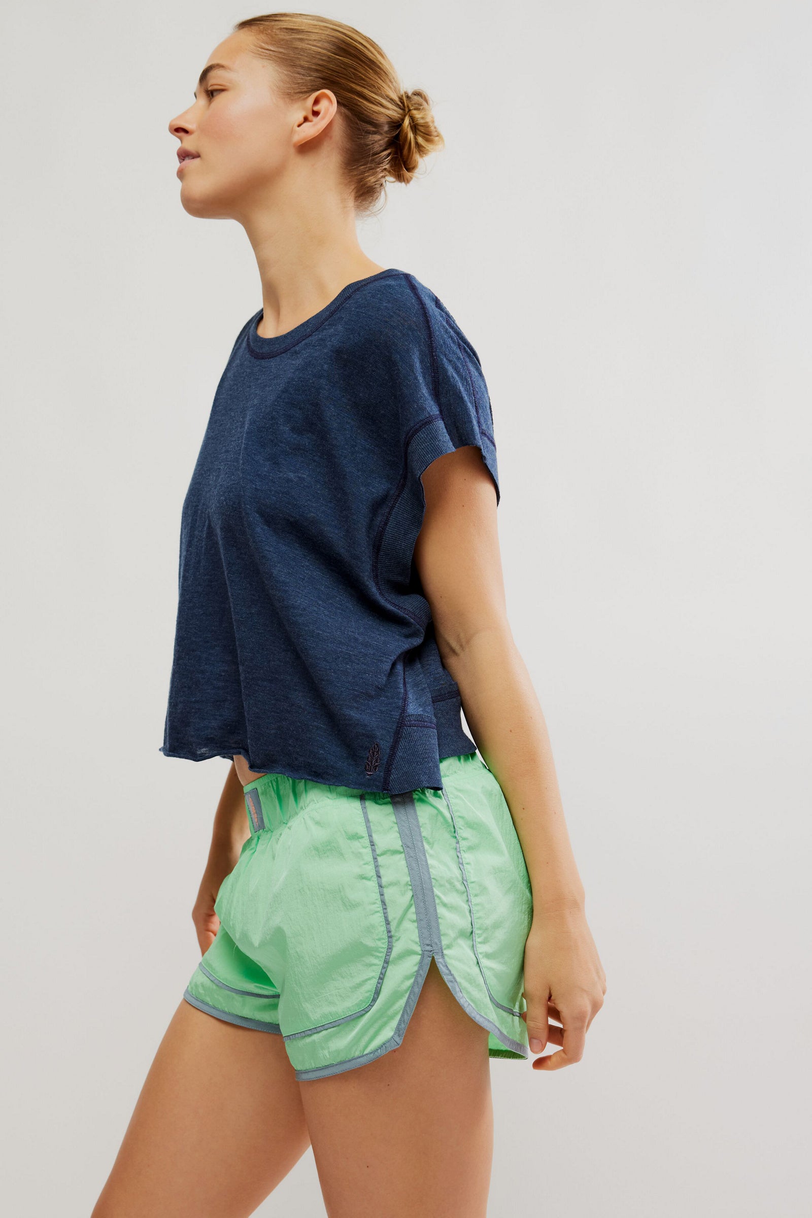 Woman wearing a blue top and green shorts on a plain background