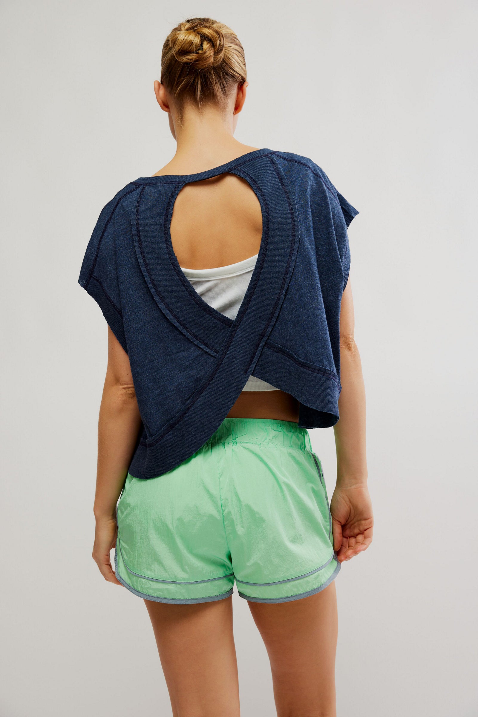 Person wearing a navy blue top and green shorts on a plain background