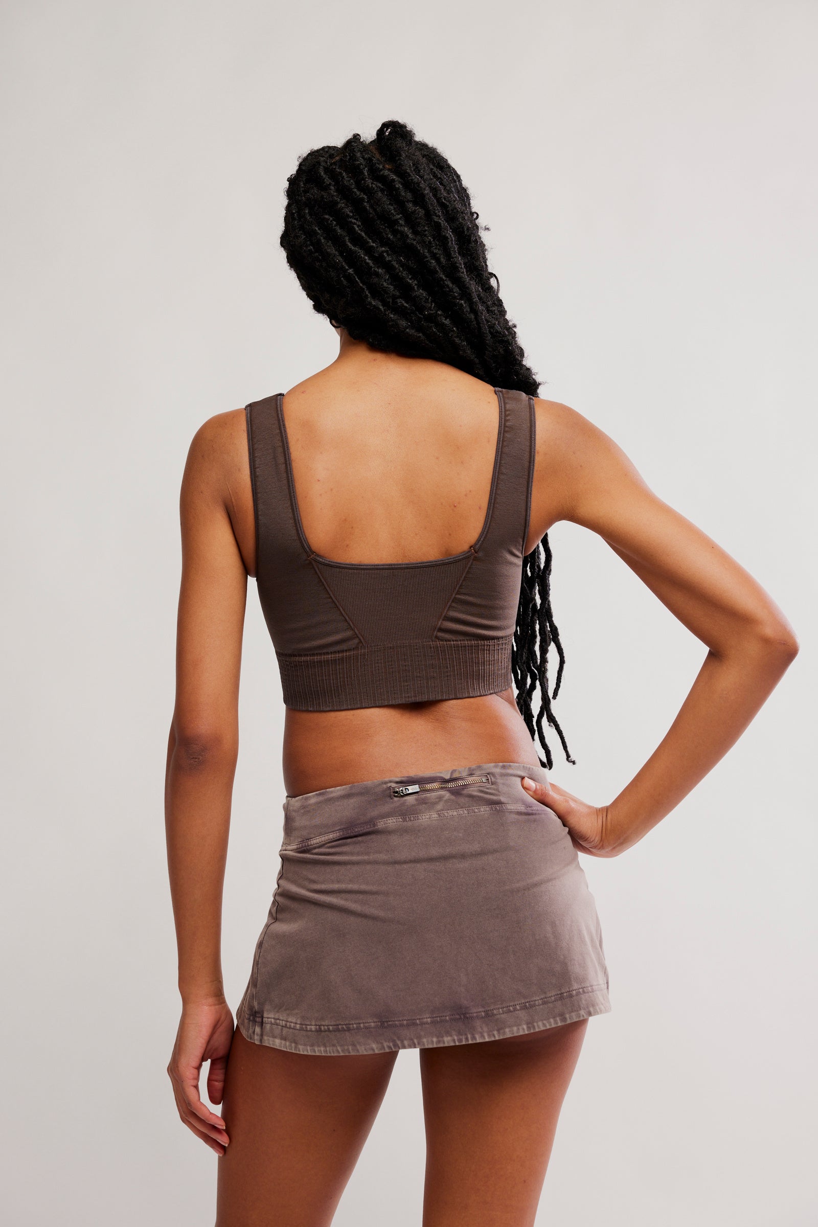 Person wearing a brown crop top and skirt against a plain background