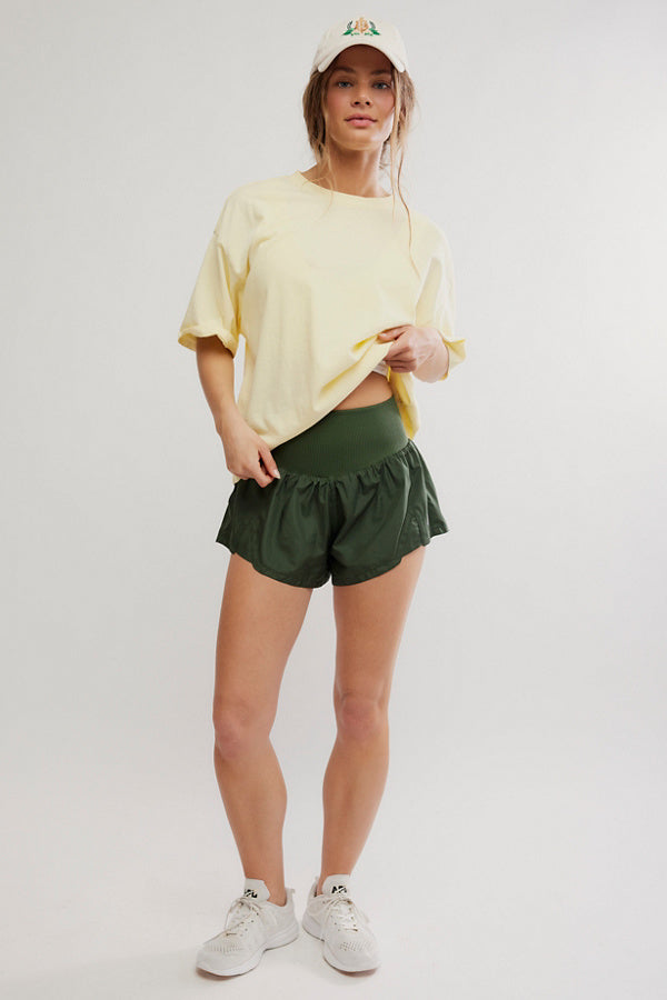 Woman wearing a yellow top and green shorts on a white background