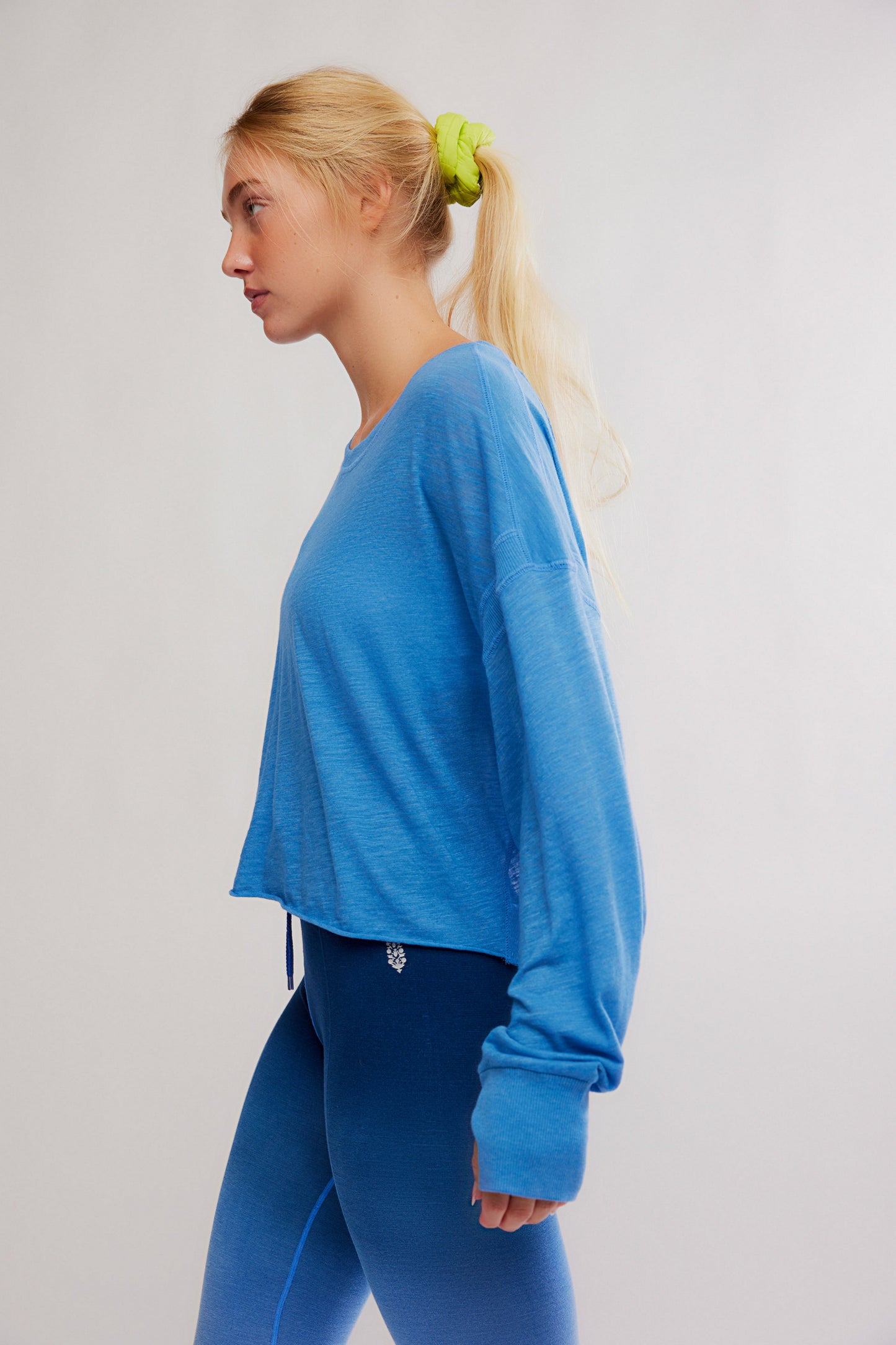 Woman wearing a blue long-sleeve top and blue pants on a light gray background