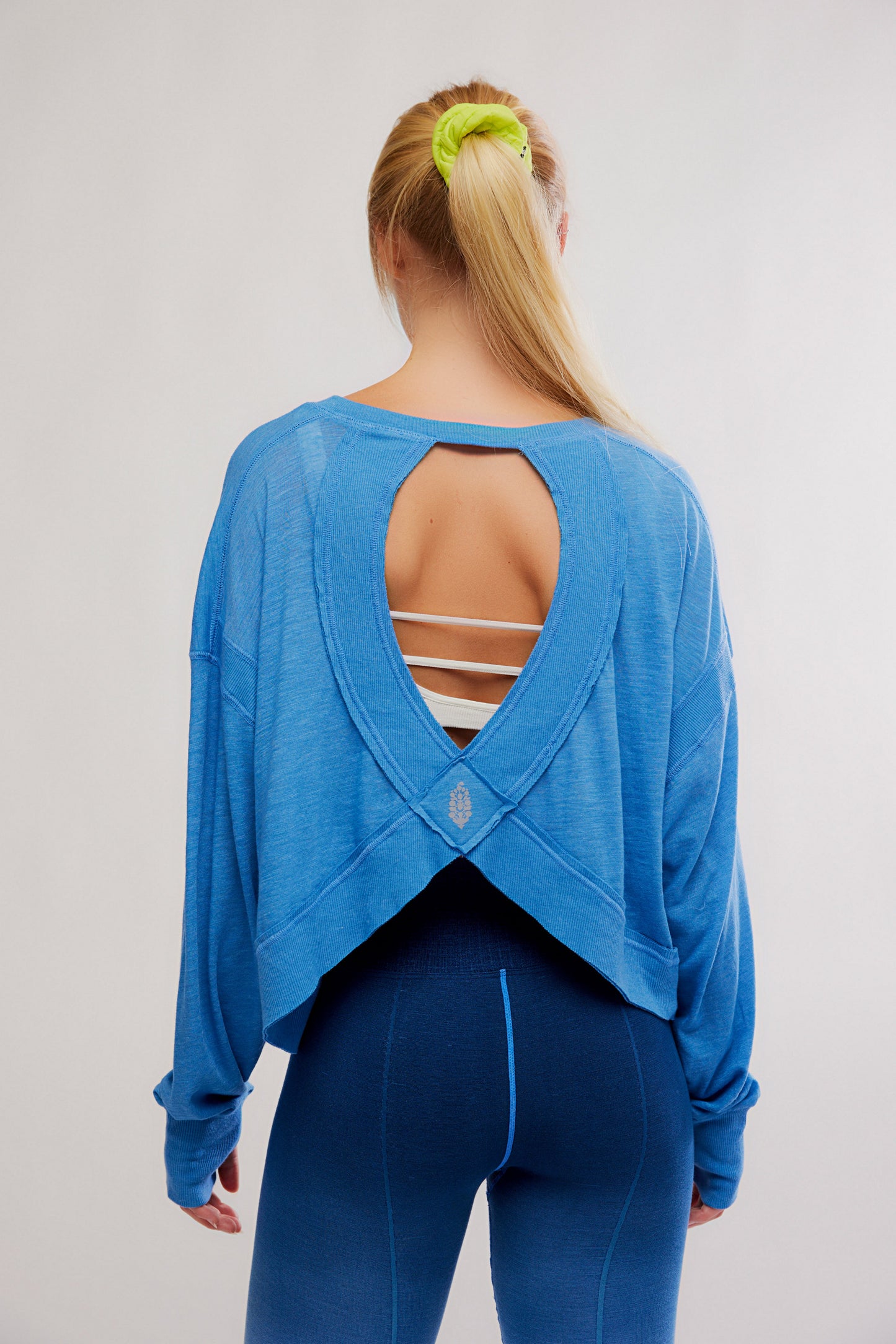 Person wearing a blue open-back top and leggings on a plain background